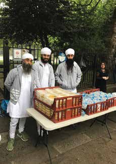 Volunteers standing behind a table of packed hot meals in a London park