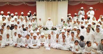 The Sangat dressed in white, seated together in a Gurdwara hall