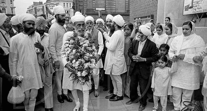 Sri Satguru Jagjit Singh Ji, garlanded with flowers, surrounded by the Sangat on a Wolverhampton street in 1976
